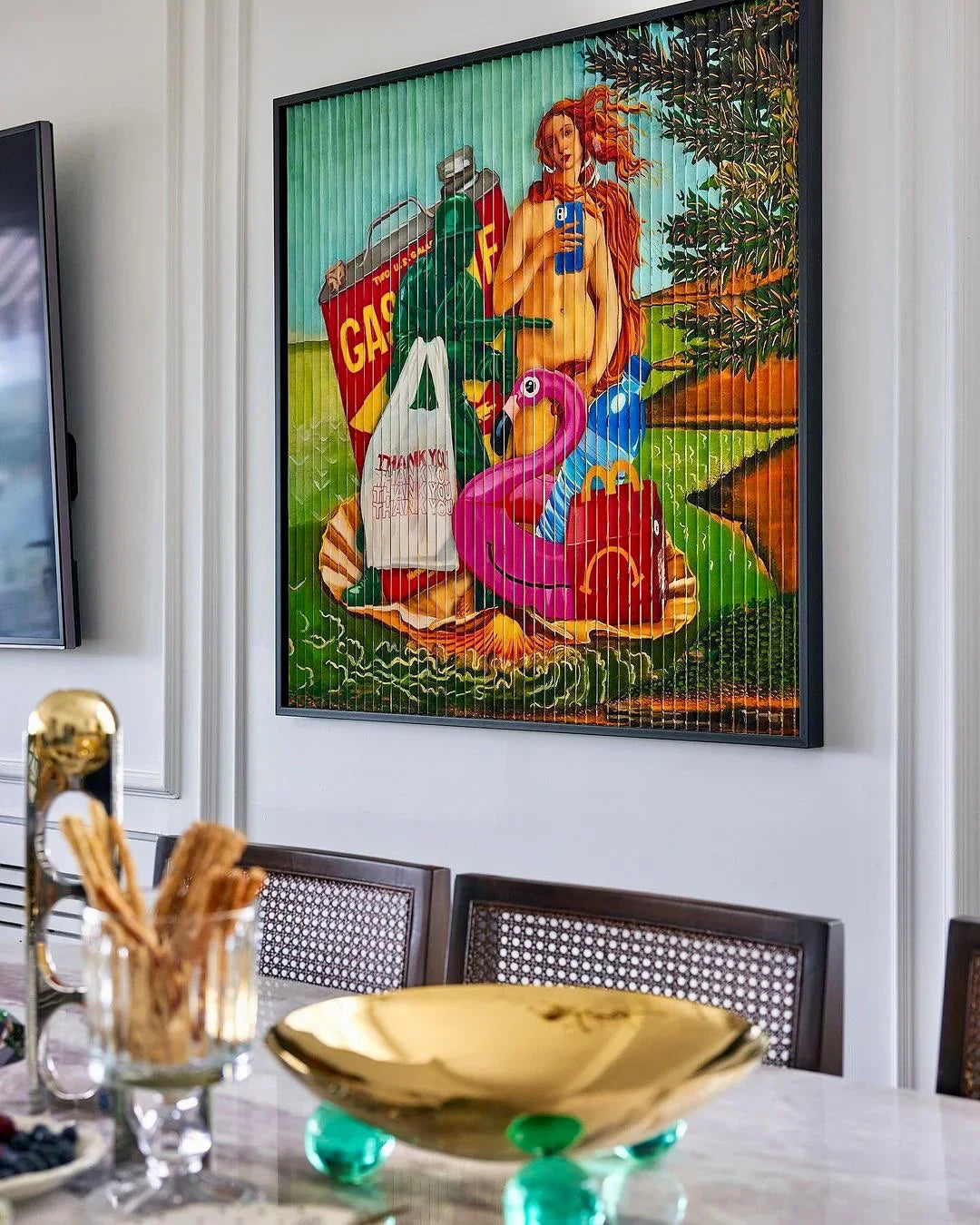 Framed pop art painting with a nude woman, pink flamingo float, gas can, and shopping bags in a modern dining room