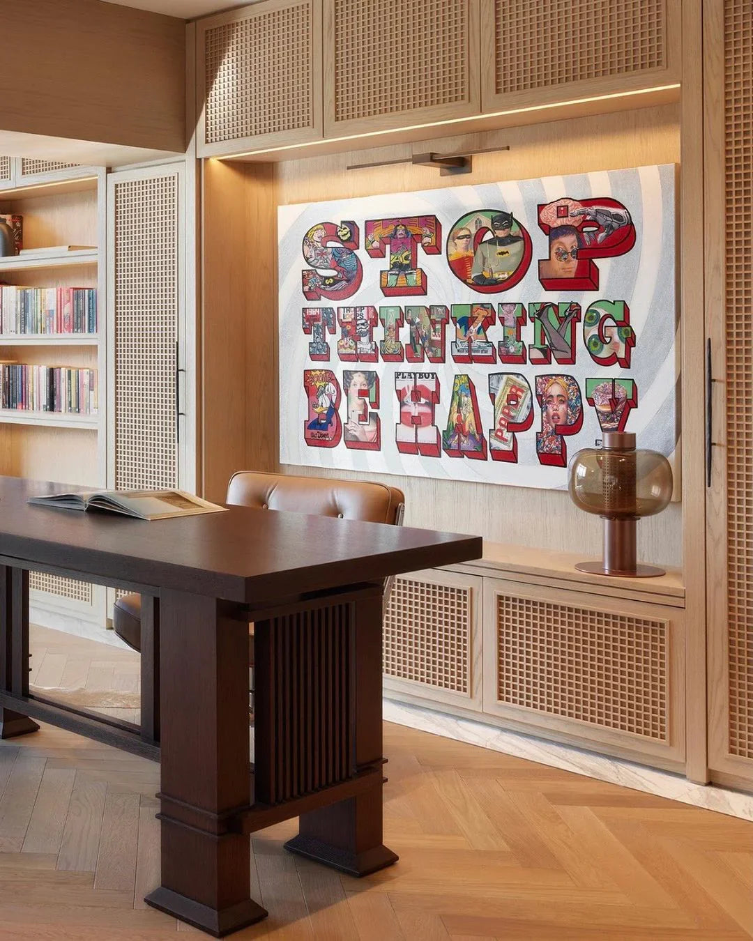 Modern office with wooden desk and colorful wall art reading Stop Thinking Be Happy